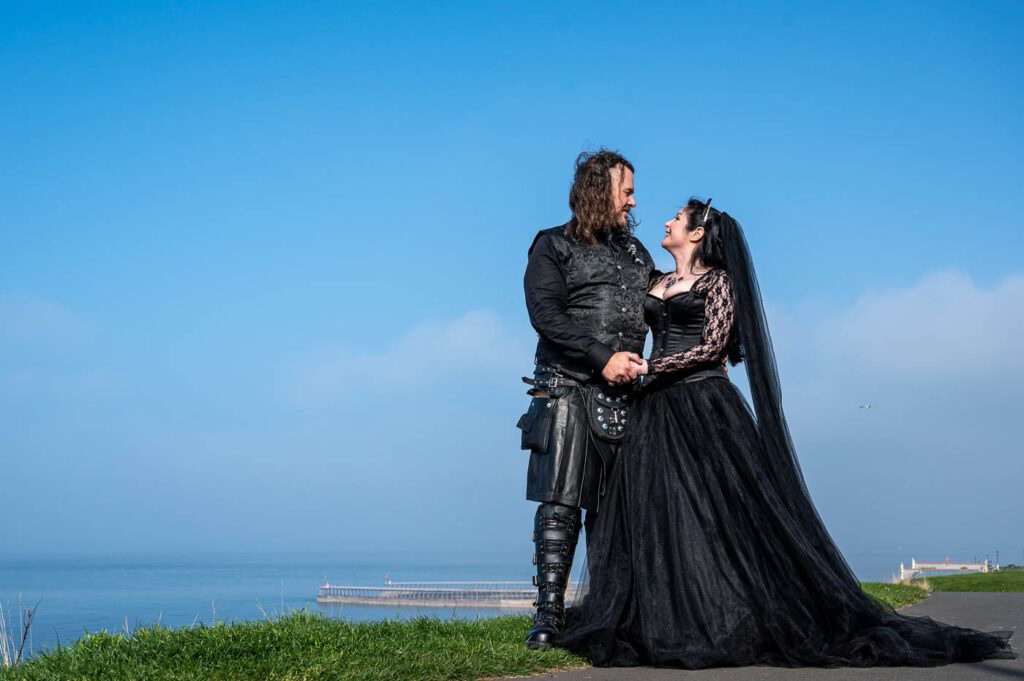 Goth bride and groom on the coastline